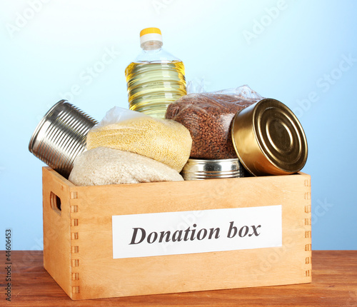 Photo: Donation box with food on blue background close-up Donation box with food on blue background close-up