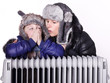 Photo: Mother and daughter in warm winter coats leaning over a radiator Mother and daughter in warm winter coats leaning over a radiator