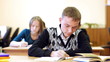 Young angry student sits at the table and shows his frustration