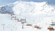 Rope-way with orange seats does descent and rise of skiers