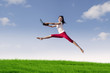 Woman with laptop jumping in meadow