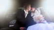 Newly-married couple sits together in limousine and kisses