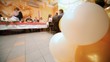 Close up balloons, behind newly-married couple kiss standing up