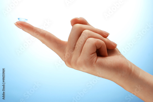 Photo: contact lens on finger on blue background contact lens on finger on blue background