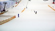 parent helps child to start go down hill in indoor ski