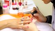 Cosmetician accurately covers nails of client with nail polish