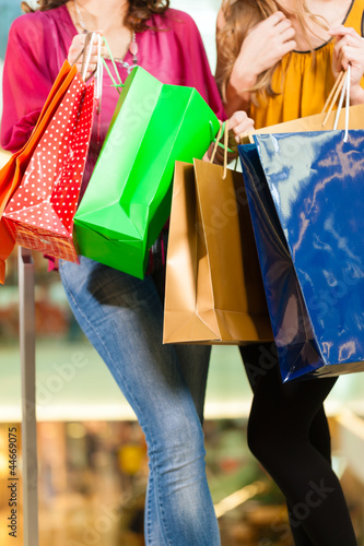 Photo: Two women shopping with bags in mall Two women shopping with bags in mall