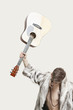 Photo: Frustrated young man in fur coat about to throw his guitar against gray background Frustrated young man in fur coat about to throw his guitar against gray background