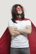 Photo: Young man in super hero costume standing with arms crossed against gray background Young man in super hero costume standing with arms crossed against gray background