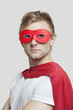 Portrait of young man wearing superhero costume against gray background