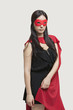 Photo: Portrait of young woman in superhero costume standing against gray background Portrait of young woman in superhero costume standing against gray background