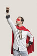 Young man in superhero costume standing against gray background