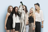 Foto: Young man drinking beer while standing with female friends against light blue background Young man drinking beer while standing with female friends against light blue background