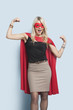 Photo: Portrait of excited young blond woman in superhero costume flexing arms over light blue background Portrait of excited young blond woman in superhero costume flexing arms over light blue background