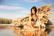 Beautiful brunette posing on river bank. Art photo.