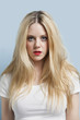 Foto: Portrait of attractive young blond woman with red lips against light blue background Portrait of attractive young blond woman with red lips against light blue background