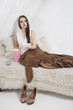 Portrait of a beautiful young woman on fur bed eating popcorn