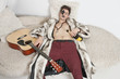 Drunk young man with guitar sleeping on sofa