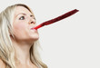 Close-up of a young woman blowing party blower against gray background