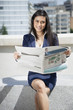 Photo: Portrait of a smart Indian businesswoman holding newspaper as she sits outdoors Portrait of a smart Indian businesswoman holding newspaper as she sits outdoors