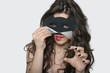 Photo: Portrait of sensuous young woman wearing cat mask while biting lip over gray background Portrait of sensuous young woman wearing cat mask while biting lip over gray background
