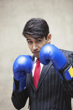 Photo: Portrait of an Indian businessman wearing blue boxing gloves against gray background Portrait of an Indian businessman wearing blue boxing gloves against gray background