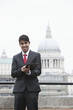 Photo: Portrait of a happy Indian businessman using tablet PC against St. Paul's Cathedral Portrait of a happy Indian businessman using tablet PC against St. Paul's Cathedral