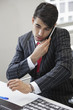 Photo: Young Indian businessman using cell phone at office desk Young Indian businessman using cell phone at office desk