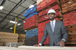 Photo: An African American male contractor standing in front of stacked wooden planks An African American male contractor standing in front of stacked wooden planks