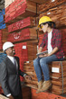 Photo: Female industrial worker and male engineer smiling while looking at each other at timber yard Female industrial worker and male engineer smiling while looking at each other at timber yard