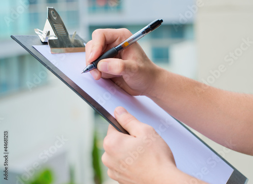 Photo: Businessman Holding A Clipboard And Writing Businessman Holding A Clipboard And Writing