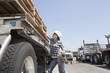 Female industrial worker strapping down wooden planks on logging truck