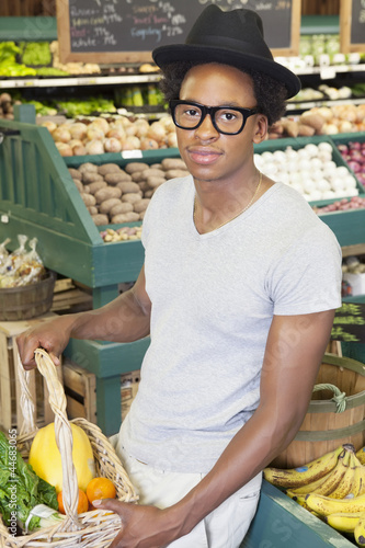 Photo: Portrait of an African American man with vegetable basket at supermarket Portrait of an African American man with vegetable basket at supermarket