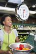 Male African American store clerk weighing bell peppers on scale