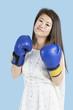 Photo: Portrait of a beautiful young woman wearing boxing gloves over blue background Portrait of a beautiful young woman wearing boxing gloves over blue background
