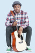 Photo: Portrait of a young African American man with guitar over light blue background Portrait of a young African American man with guitar over light blue background
