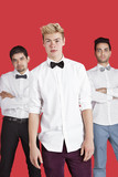 Photo: Portrait of a young man standing in front of male friends over red background Portrait of a young man standing in front of male friends over red background