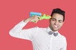 Foto: Frustrated man holding toy gun to his head over red background Frustrated man holding toy gun to his head over red background