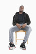 Photo: Portrait of a trendy African American man sitting on chair over gray background Portrait of a trendy African American man sitting on chair over gray background