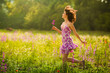 Beautiful young woman running in purple flowers outdoors