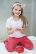 Portrait of girl with piggy bank and coins sitting in bed