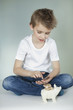 Boy with piggy bank counting coins over gray background