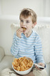 Boy watching TV while eating wheel shape snack pellets