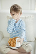 Photo: Little boy watching scary movie with a bowl full of wheel shape snack pellets Little boy watching scary movie with a bowl full of wheel shape snack pellets
