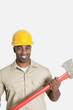 Foto: Portrait of happy African male construction worker holding axe over gray background Portrait of happy African male construction worker holding axe over gray background