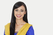 Photo: Portrait of an attractive Indian woman in traditional wear smiling against gray background Portrait of an attractive Indian woman in traditional wear smiling against gray background