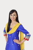 Photo: Portrait of beautiful Indian woman in traditional wear standing with hands on hips over gray background Portrait of beautiful Indian woman in traditional wear standing with hands on hips over gray background