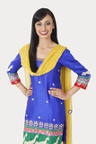 Photo: Portrait of pretty Indian woman in traditional wear standing with hands on hips over gray background Portrait of pretty Indian woman in traditional wear standing with hands on hips over gray background