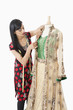 Photo: Indian female dressmaker working on a traditional outfit over gray background Indian female dressmaker working on a traditional outfit over gray background