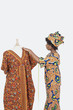 Photo: Female tailor in traditional outfit measuring dashiki on tailor's dummy over gray background Female tailor in traditional outfit measuring dashiki on tailor's dummy over gray background